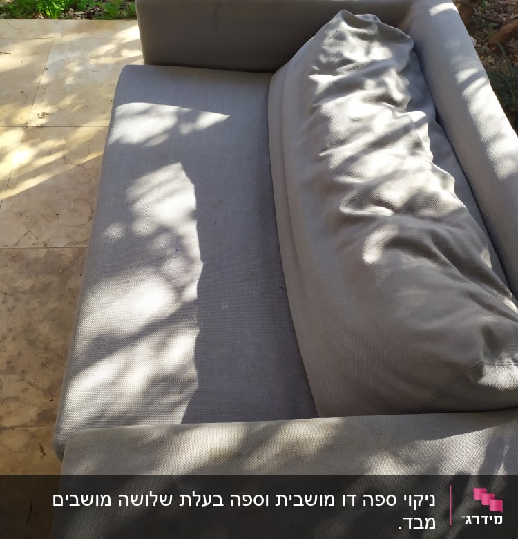 ספה אפורה עם כרית על משטח אבן